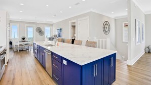 A spacious kitchen with a large island, white cabinetry, and a modern design. - Scenic waterfront home with five bedrooms & easy beach access - dog-friendly (St. George Island)