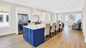 A modern kitchen with a central island, built-in appliances, and a dining area with chairs. - Scenic waterfront home with five bedrooms & easy beach access - dog-friendly (St. George Island)