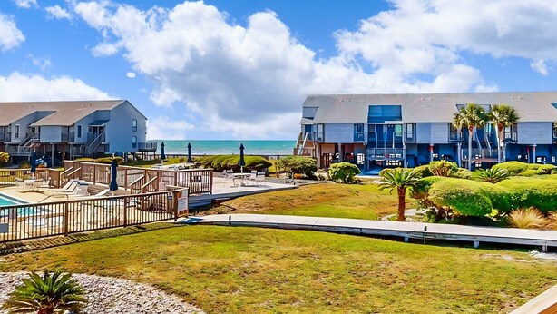 Hotel frente a la playa con piscina, mobiliario exterior y vista al océano.
