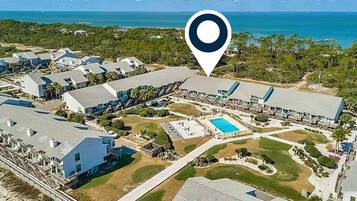 An aerial view of a resort with multiple buildings, a swimming pool, and a beachfront.