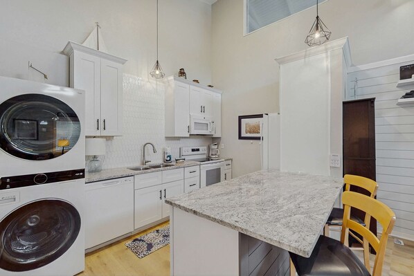A compact kitchen with a central island, built-in appliances, and a dining area with yellow chairs. - Great, dog-friendly home with Gulf views, shared pool, just steps from the Gulf (St. George Island)