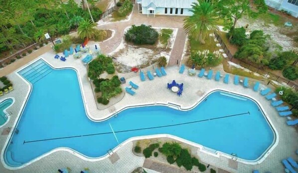 Una grande piscina con diverse zone relax e palme.