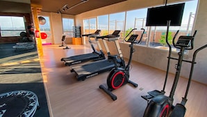 Un gimnasio con cintas de correr, una bicicleta estática y un trampolín.