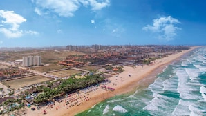 Vista aérea de una ciudad costera con una playa extensa, edificios altos y un cielo despejado.