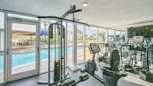 Een sportschool met trainingsapparatuur, een zwembad en grote ramen.