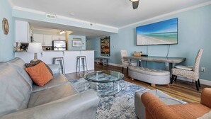 Een moderne woonkamer met een glazen salontafel, een bank en een eethoek met uitzicht op het strand.