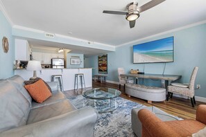 Ein modernes Wohnzimmer mit einem Glastisch, einer Couch und einem Essbereich mit Blick auf den Strand.