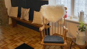 Una habitación acogedora con un banco de madera, un reloj antiguo y un cuadro en la pared.