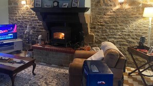Una sala de estar acogedora con una pared de piedra, chimenea, televisor y un espacio de descanso cómodo.