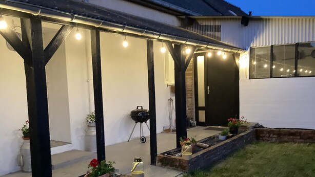Un espacio exterior techado con una parrilla y plantas en macetas.