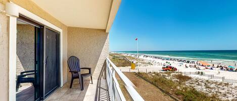 Un balcón con vista a la playa, una silla y una puerta.