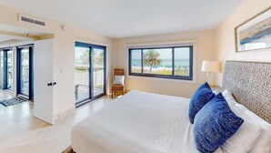 Quarto com uma cama grande, vista para a praia e porta de correr de vidro para o exterior.