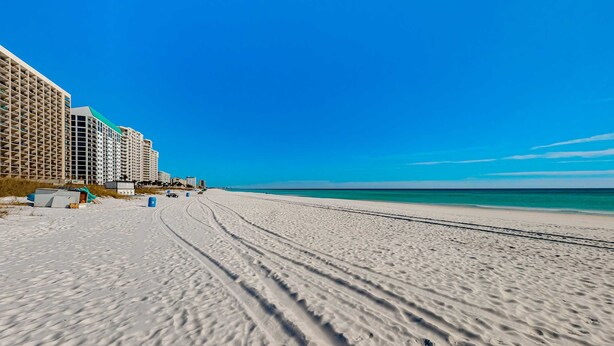 A beach with a row of high-rise buildings, sandy beach, and clear blue sky. - 2nd-floor condo with beach access, pool, tennis courts, & on-site laundry (Destin)