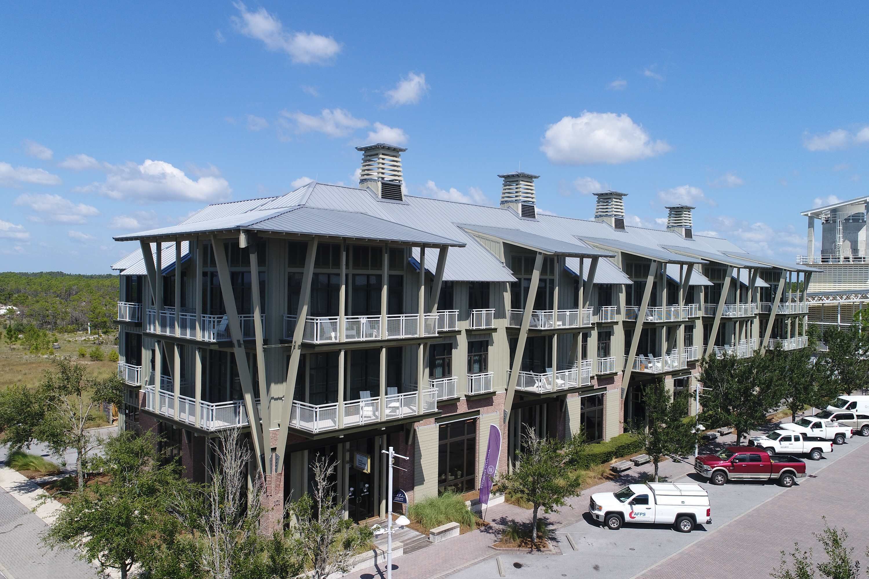 A modern building with multiple balconies and a parking area.