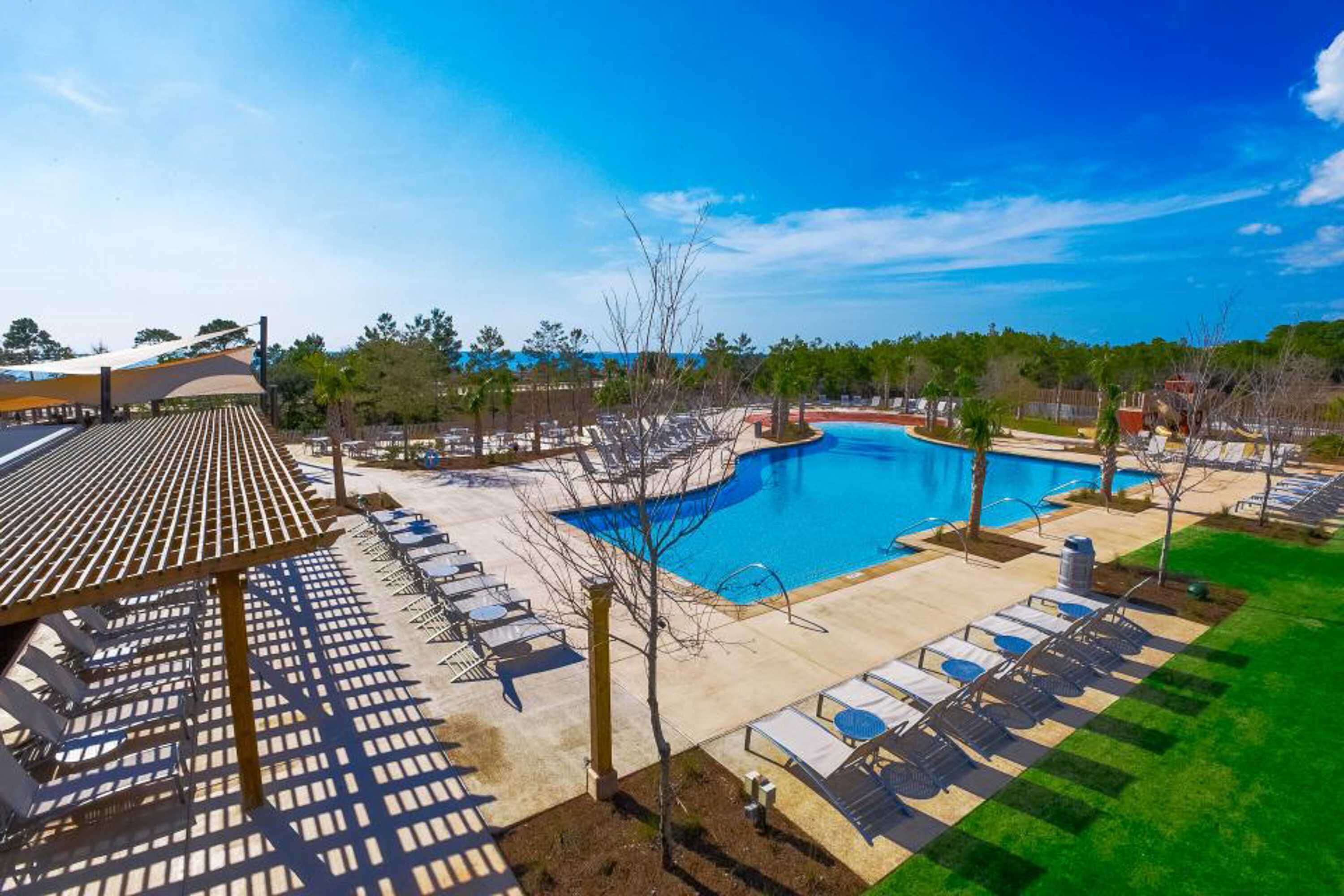 A pool area with lounge chairs and a covered seating area.