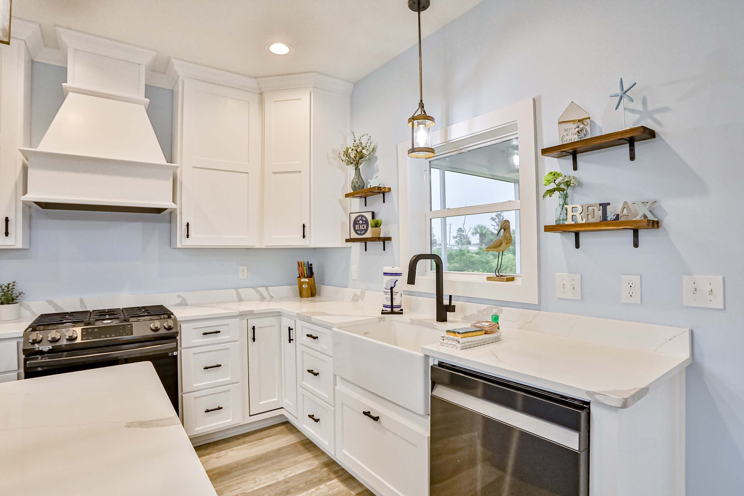 A modern kitchen with white cabinetry, a stainless steel dishwasher, and a built-in oven.