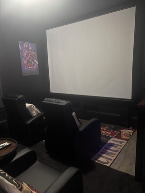 A home theater setup with a large screen, reclining chairs, and a popcorn machine.