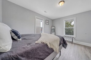 A bedroom with a bed, a window, and a ceiling light.