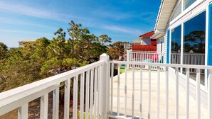A white balcony with a red roof, surrounded by trees and a clear sky. - Beach Across the Street! Dog-Friendly Home with Private Pool, AC, WiFi & Games! (St. George Island)