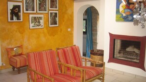 Una sala de estar con dos sillones a rayas, un sofá, una chimenea y varias imágenes enmarcadas en la pared.