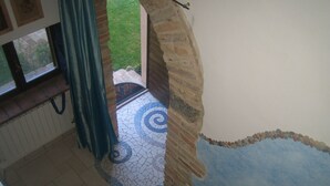 Una escalera con suelo de mosaico azul y blanco, un arco de piedra y vistas a un jardín exterior.