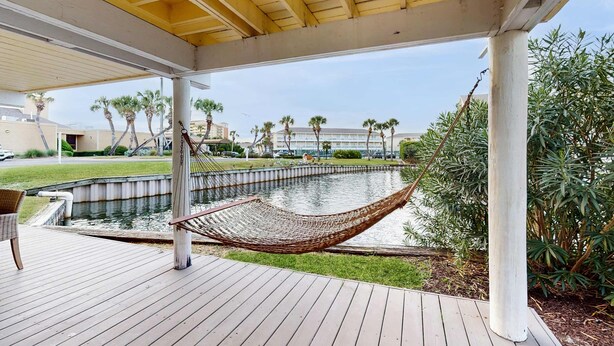 A wooden deck with a hammock, a small pond, and palm trees. - Waterfront villa with multi level home, shared pool & easy beach access (Destin)