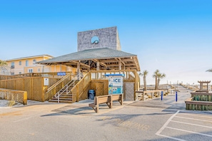 A beachside building with a wooden structure, a staircase, and a sign for 'Baggage Ice'.