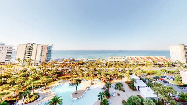 Un resort con piscina, palmeras y vistas a la playa.