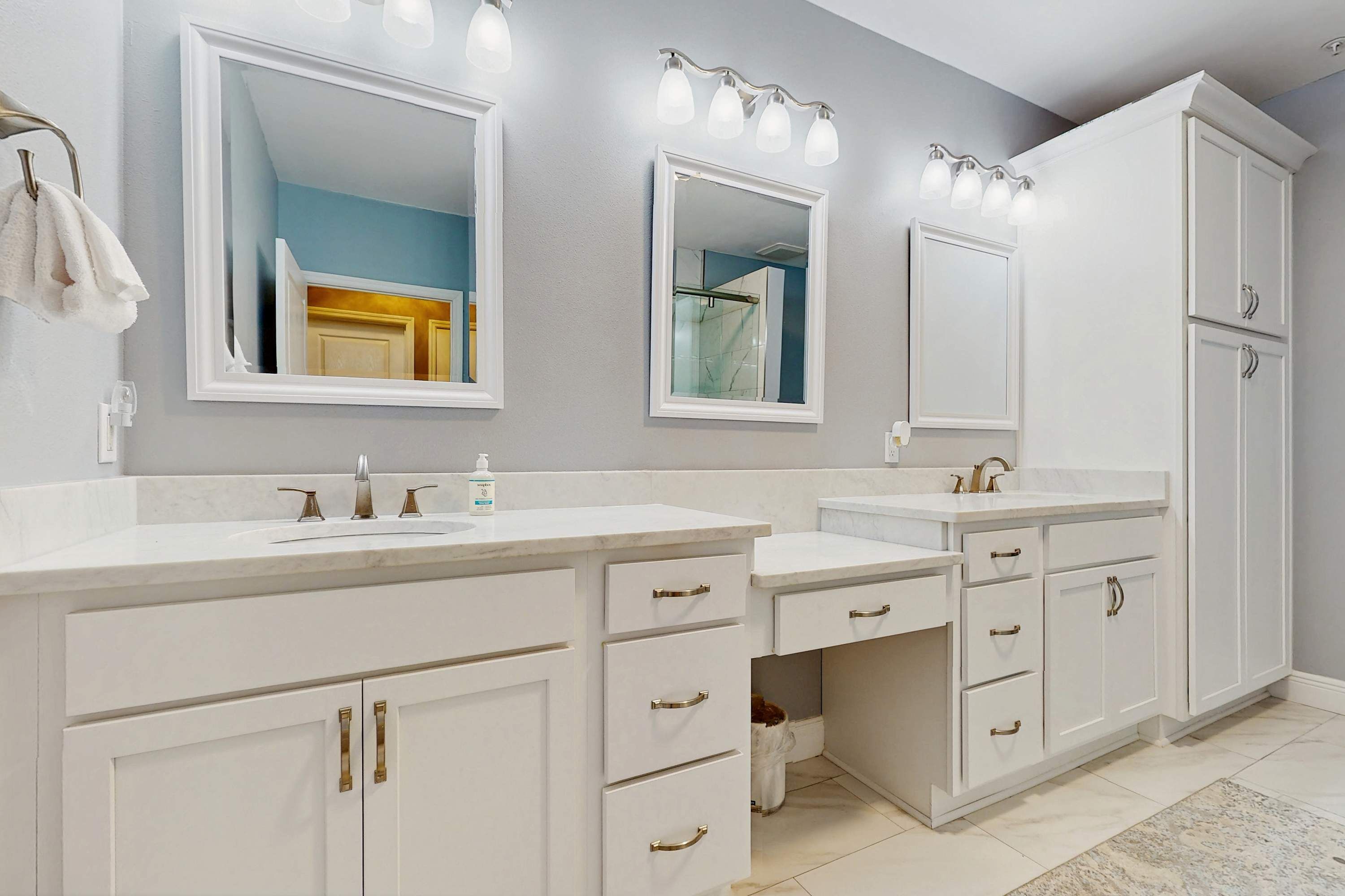 A modern bathroom with two sinks, large mirrors, and a walk-in shower.
