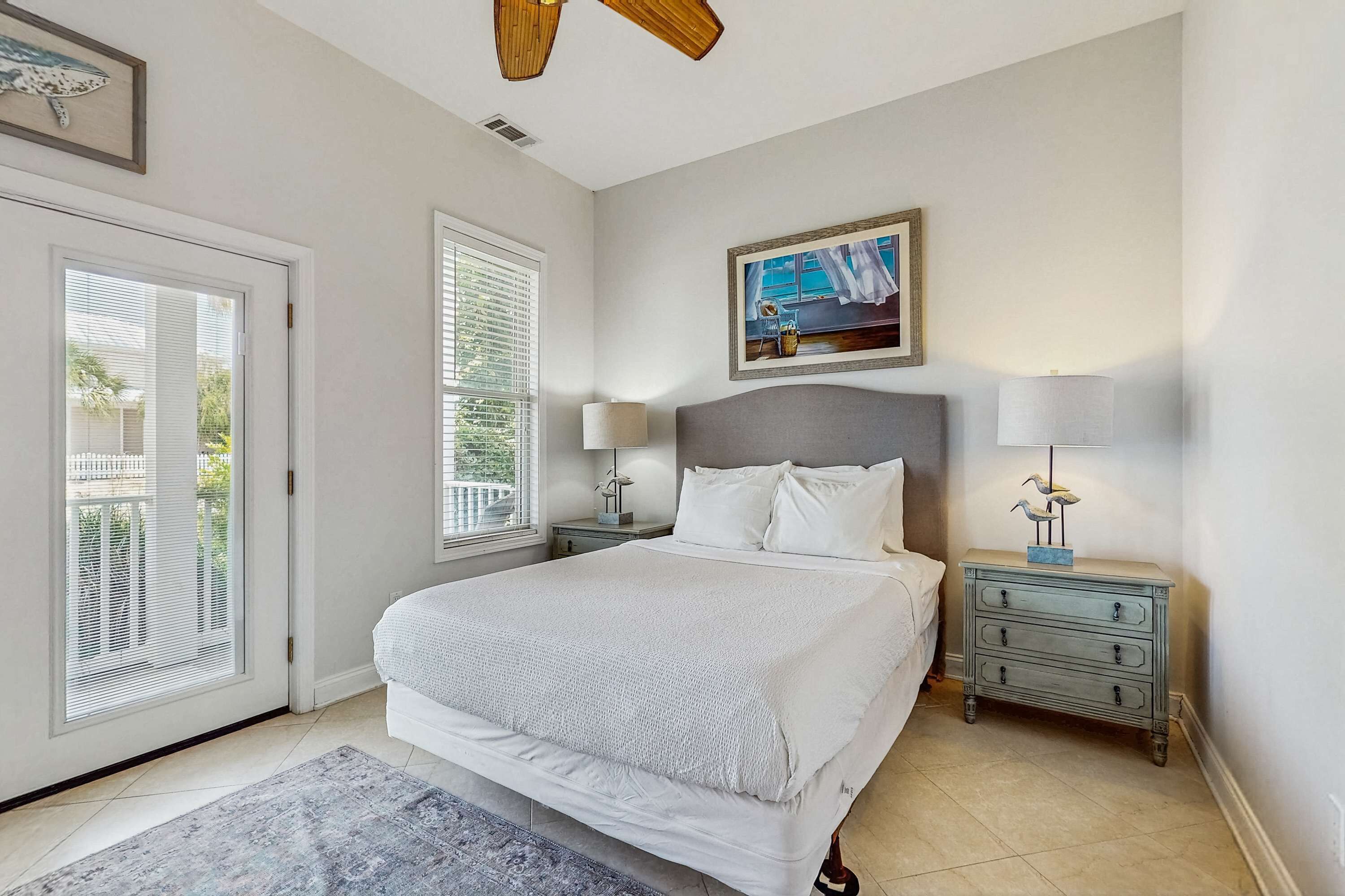 A bedroom with a large bed, a nightstand with a lamp, a dresser, and a painting on the wall.