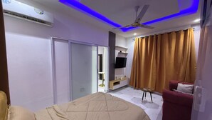 Ein modernes Hotelzimmer mit einem Bett, einem Fernseher, einem Deckenventilator und einer Sitzecke.