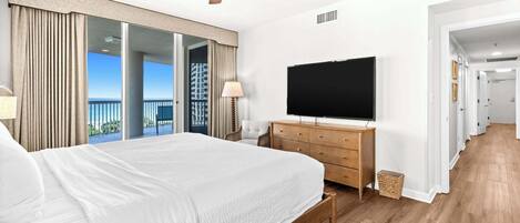 Une chambre avec un grand lit, un ventilateur de plafond, une tĂ©lĂ©vision et une vue sur lâextĂ©rieur.