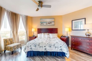 A hotel room with a bed, a chair, a dresser, and a ceiling fan. - Seventh floor inviting, open condo w shared pool & hot tub near everything (Destin)