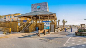 Un bâtiment situé au bord de la plage, avec une structure en bois, un escalier et une enseigne indiquant « Rock Sand Trap ».