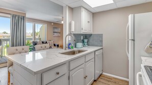 Une cuisine moderne dotée d’un grand îlot central, de meubles blancs et d’un lave-vaisselle encastré.