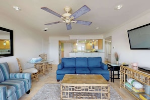 Ein Wohnzimmer mit einem blauen Sofa, einem Couchtisch und einem Deckenventilator.