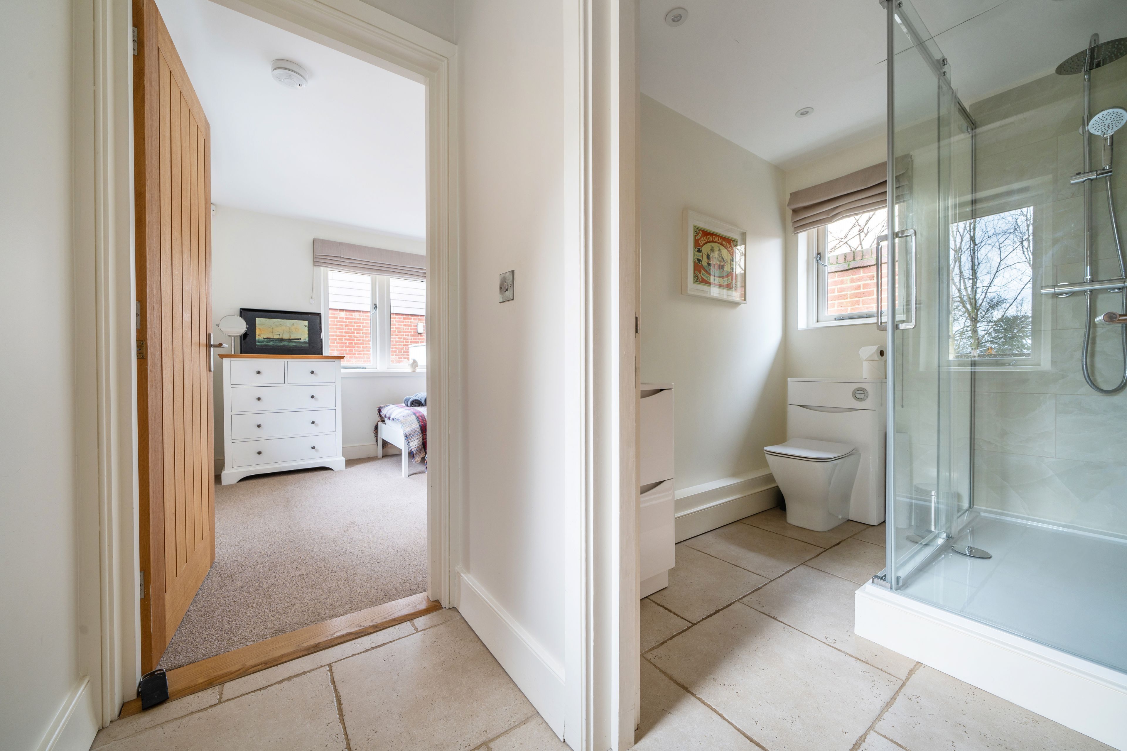 A modern bathroom with a glass shower enclosure, a toilet, and a sink.