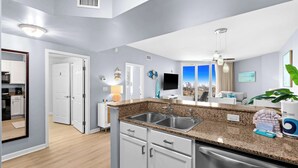 Una cocina moderna con encimeras de granito, electrodomésticos de acero inoxidable y vistas a la ciudad a través de amplios ventanales.