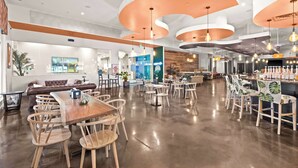 Un espacio interior amplio con una mesa de madera, varias sillas y una zona de bar con taburetes.