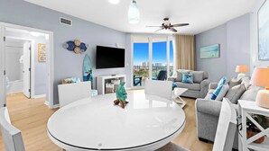 Una sala moderna con una mesa redonda, un televisor de pantalla plana y un balcón con vistas a la ciudad.