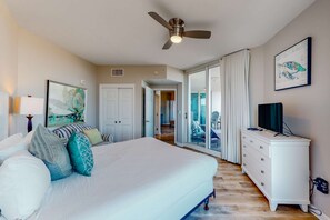 Ein Schlafzimmer mit Bett, Deckenventilator, Kommode und Fernseher.