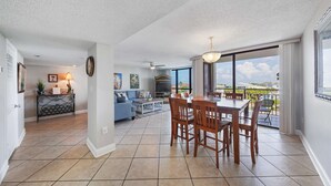 Amplia sala de estar con una mesa de comedor, sofás y vistas al exterior.