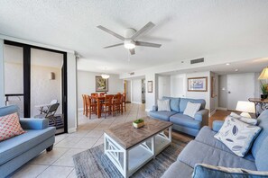 Ein geräumiger Wohnbereich mit Deckenventilator, einem Esstisch mit Stühlen und einer Couch mit gemusterten Kissen.