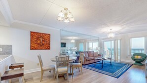 A spacious living area with a dining table, chairs, a sofa, and a large mirror. - Spacious, 3rd-floor beachfront condo with stunning views, pool, pickleball, & AC (Fort Walton Beach)