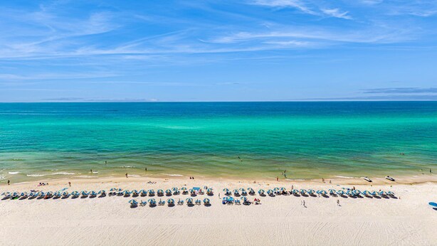 Ein Strand mit Reihen von Strandstühlen und Liegestühlen.