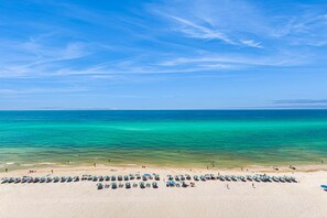 A beach with rows of beach umbrellas and lounge chairs. - Eighth-floor beachfront condo w/ hot tubs, pools, seasonal beach service & more (Panama City Beach)