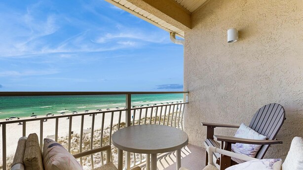 Un balcone con vista sulla spiaggia, un tavolo rotondo e due sedie.