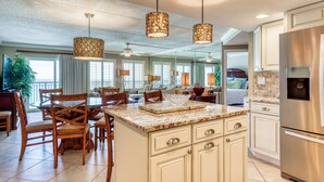 A spacious kitchen with a large island, wooden chairs, and pendant lighting. - 6th-floor, updated condo with beach service - near dining (Fort Walton Beach)