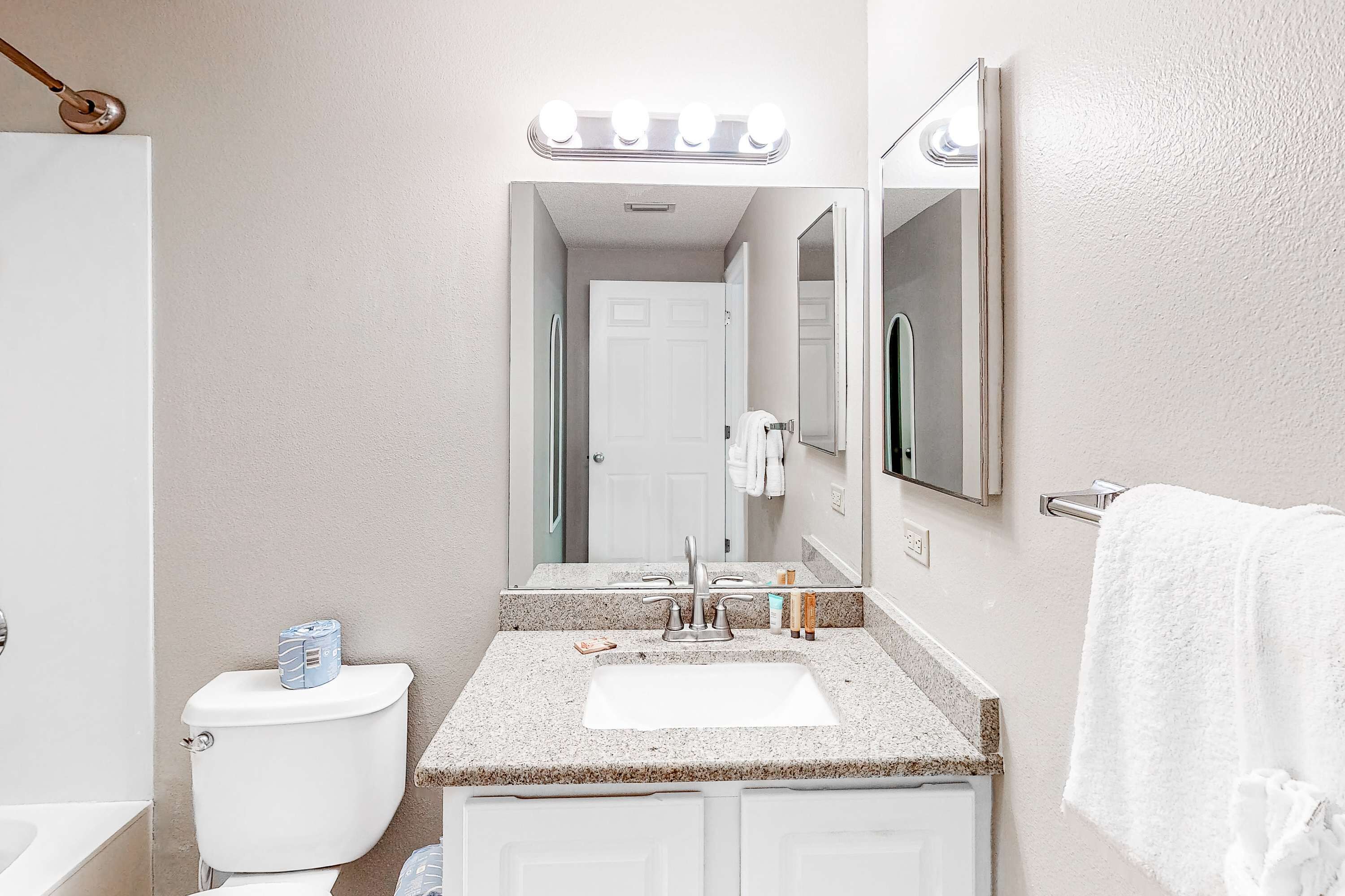 A bathroom with a white toilet, a sink with a mirror above it, and a towel hanging on a rack.