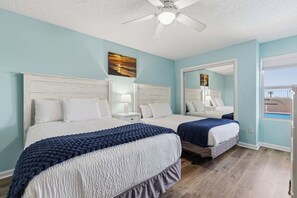 Ein Hotelzimmer mit zwei Betten, einem Deckenventilator, einem großen Spiegel und Blick ins Freie.